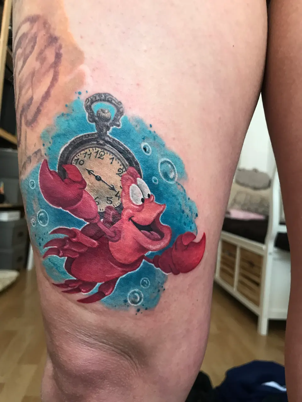 Krabbe Sebastian mit Taschenuhr und Luftblasen als Tattoo