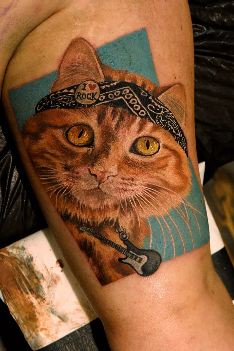 Rote Katze mit Bandana und Gitarre als Tattoo