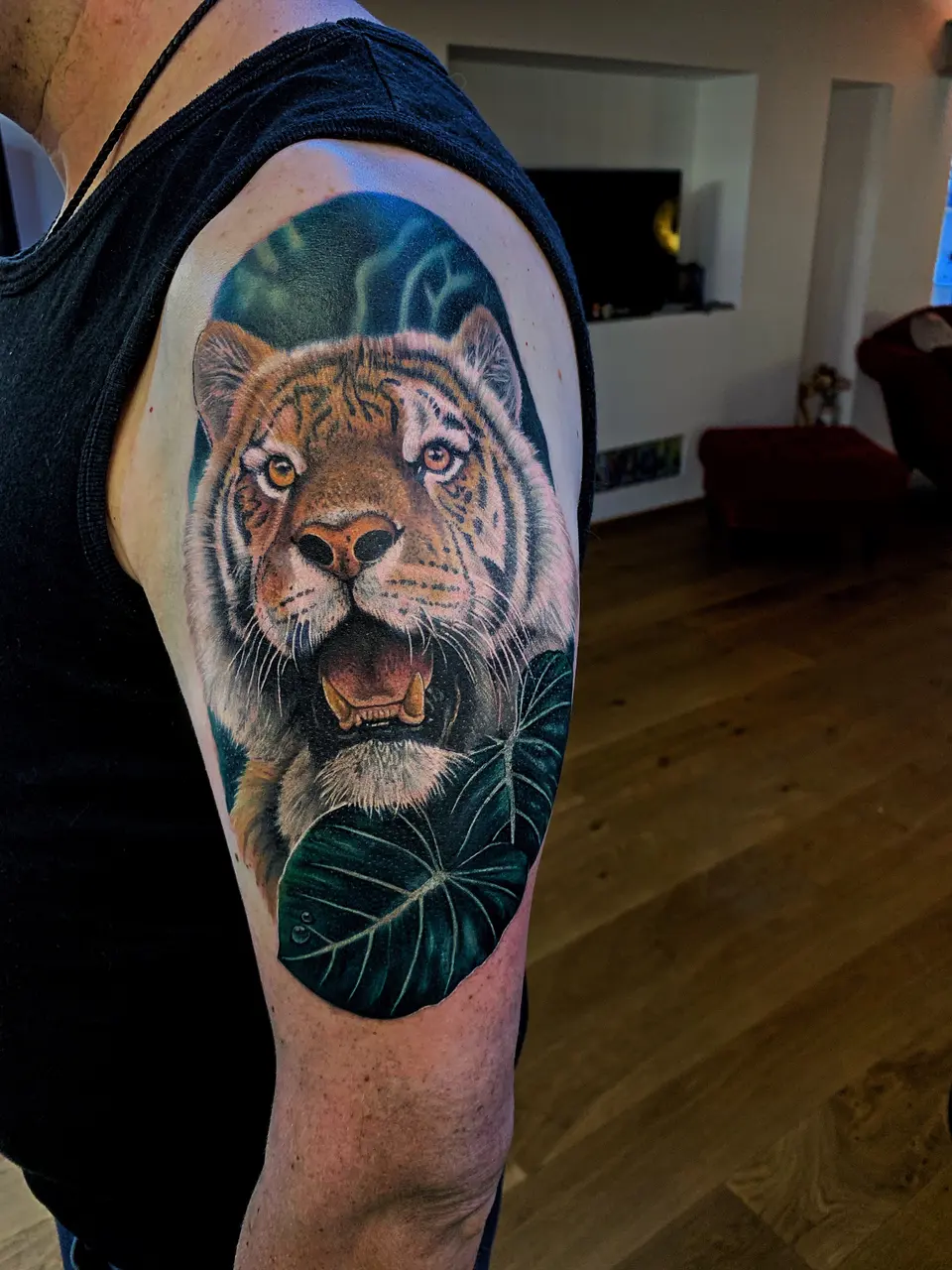 Tiger mit Monstera-Blättern als Schulter-Tattoo